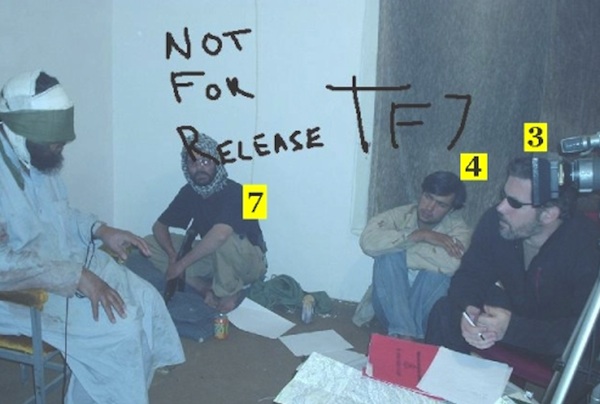 This photo, obtained by the blogger "Soj", shows an interrogation of an Afghan suspect by US bounty hunter, Jonathan Keith Idema, formerly a US special forces soldier. Note that it shows the subject being videotaped with a camera set up at approximately his eye level and that he is seated against a wall. Unlike Berg, he has been blindfolded and his hands are tied. A guard (7), a translator (4), and Idema (3), are sitting out of shot. Idema probably learned this method of recording an interrogation while serving with US special forces. (The notation "NOT FOR RELEASE TF7" refers to Idema's Task Force Sabre 7 group and was probably written by Idema