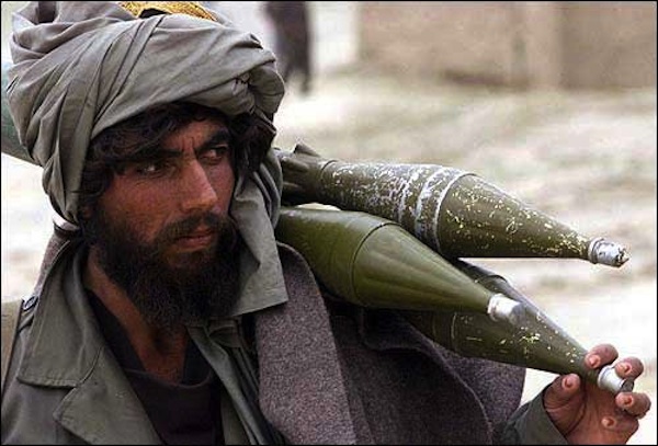 An Afghan fighter loyal to the interim government carries rockets on his shoulder in Khoja Kotkai, 25 miles west of Kabul, Afghanistan. Plumes of smoke rose Saturday from the rocky hills west of Kabul, as forces loyal to the interim Afghan government lobbed shells at positions held by a local warlord.