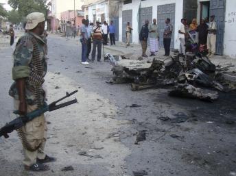 A Somali soldier stands at the scene of a suicide car bomb