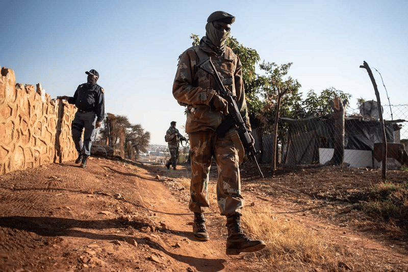 A photo of an SANDF Soldier (centre) and a SAPS Officer (left) makes the rounds on South African Social Media Platforms as Rumours Spread of Deployment of the South African Army within the country
